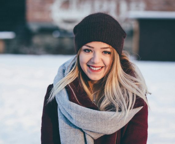 smiling woman wearing brown scarf and maroon coat on snow field